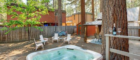 Un patio trasero con jacuzzi, mobiliario exterior y una terraza de madera.