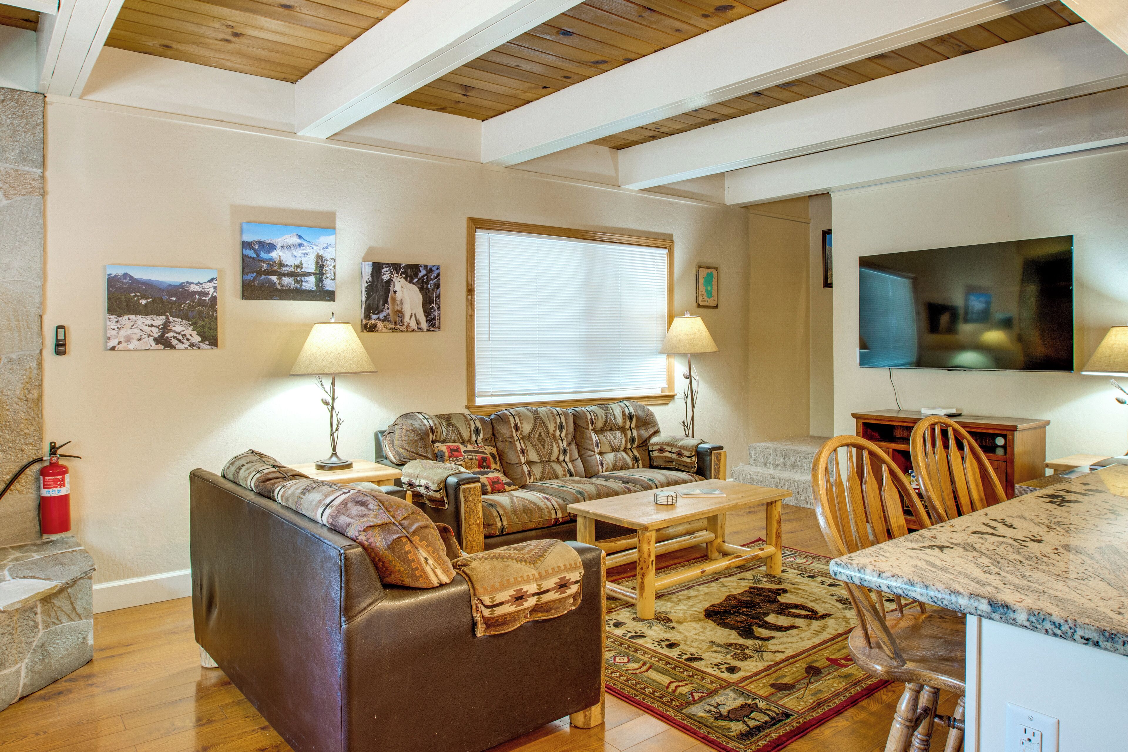 A living room with a sofa, coffee table, and chairs, a television, and wall-mounted artwork.