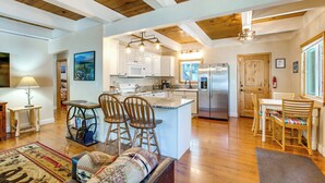 A spacious kitchen with white cabinets, a central island with bar stools, and a stainless steel refrigerator. - Minutes to Slopes & Shore! Cozy Cabin w/ hot tub (South Lake Tahoe)