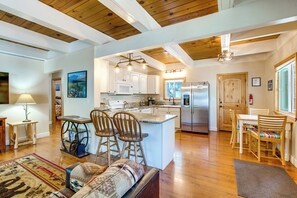 A spacious kitchen with white cabinets, a central island with bar stools, and a stainless steel refrigerator. - Minutes to Slopes & Shore! Cozy Cabin w/ hot tub (South Lake Tahoe)
