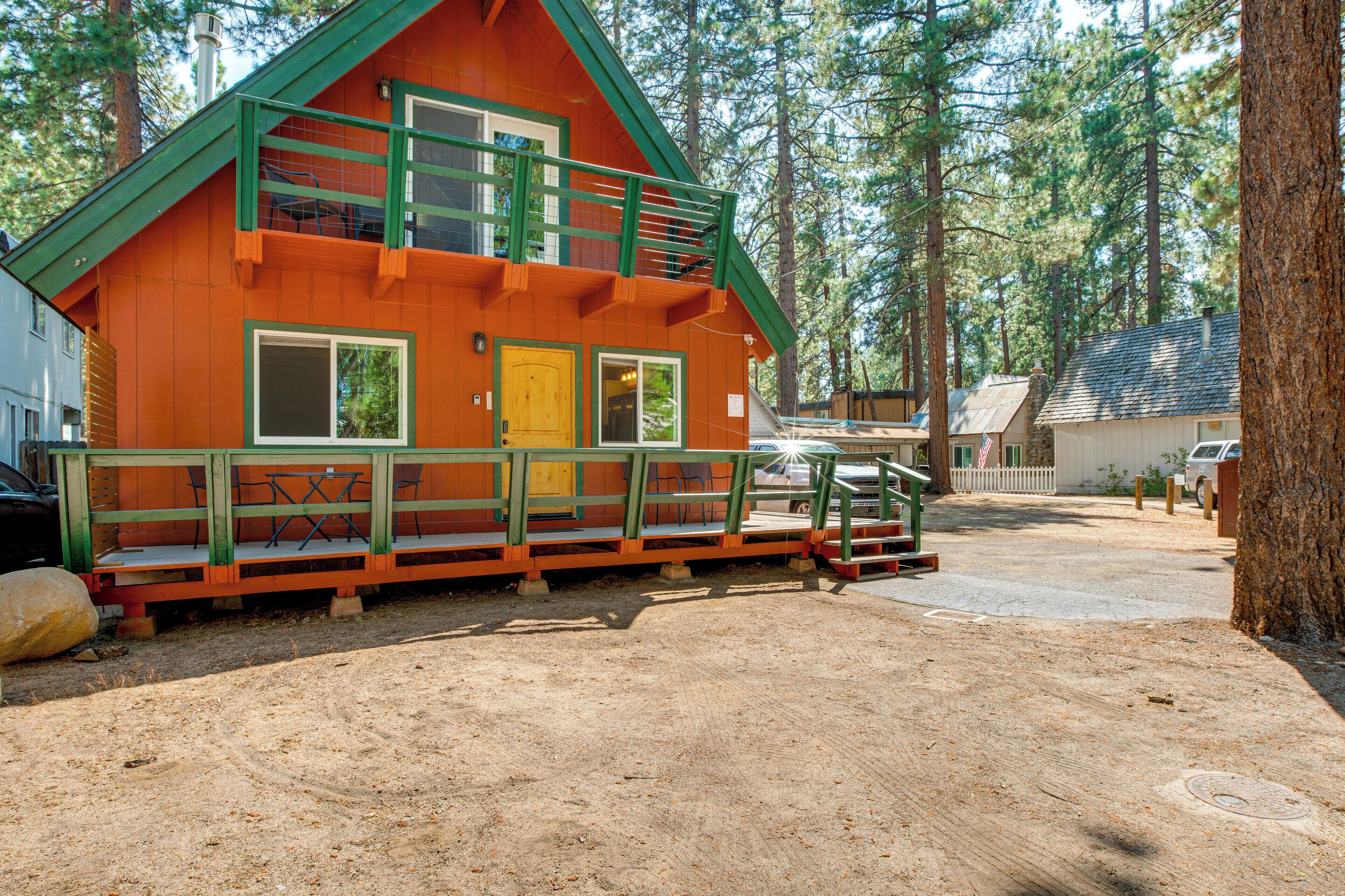Une cabane à deux étages avec un balcon verdoyant, une porte d’entrée et un petit espace porche.