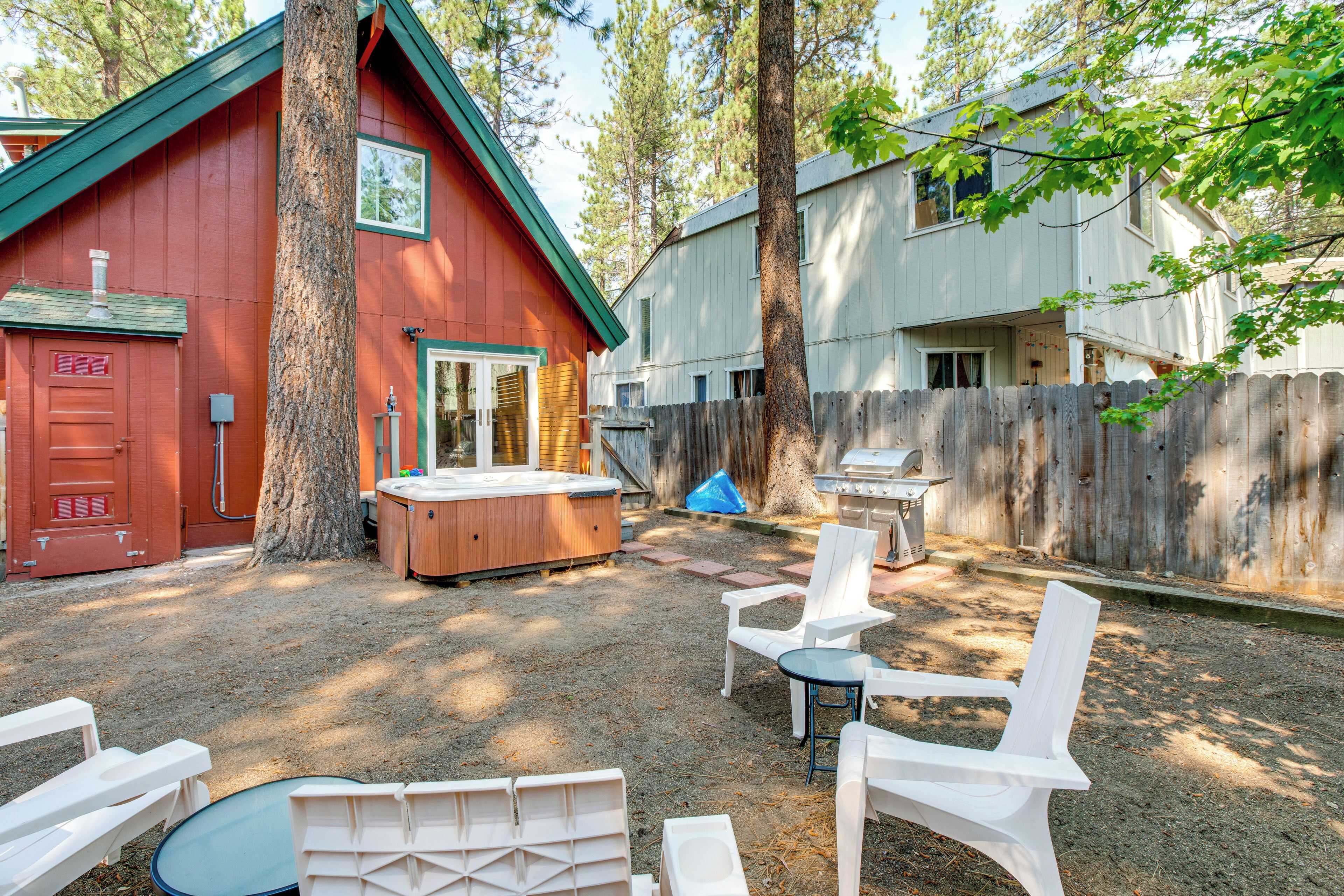 A backyard with a hot tub, outdoor seating, and a wooden fence.