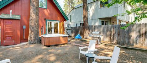 A backyard with a hot tub, outdoor seating, and a wooden fence.