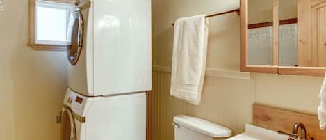 A compact bathroom with a washing machine, toilet, and sink.