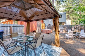 Eine Terrasse im Freien mit überdachter Sitzgelegenheit, einem Whirlpool und einem Grill.