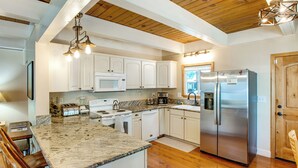 A kitchen with white cabinets, a stainless steel refrigerator, a granite countertop, and a wooden ceiling. - Minutes to Slopes & Shore! Cozy Cabin w/ hot tub (South Lake Tahoe)