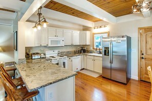 A kitchen with white cabinets, a stainless steel refrigerator, a granite countertop, and a wooden ceiling. - Minutes to Slopes & Shore! Cozy Cabin w/ hot tub (South Lake Tahoe)