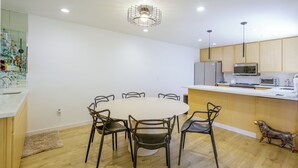 A modern kitchen with wooden cabinets, a central island with a microwave, and a dining area with a round table and chairs. - Walk to El Paseo Shops! Palm Desert Condo w/ Patio (Palm Desert)