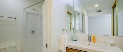 A bathroom with a shower, toilet, sink, and mirror.