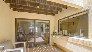 A patio area with a sliding glass door leading to an outdoor space, a tiled backsplash, and a window with a view of the interior. - Walk to El Paseo Shops! Palm Desert Condo w/ Patio (Palm Desert)