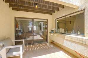 A patio area with a sliding glass door leading to an outdoor space, a tiled backsplash, and a window with a view of the interior. - Walk to El Paseo Shops! Palm Desert Condo w/ Patio (Palm Desert)