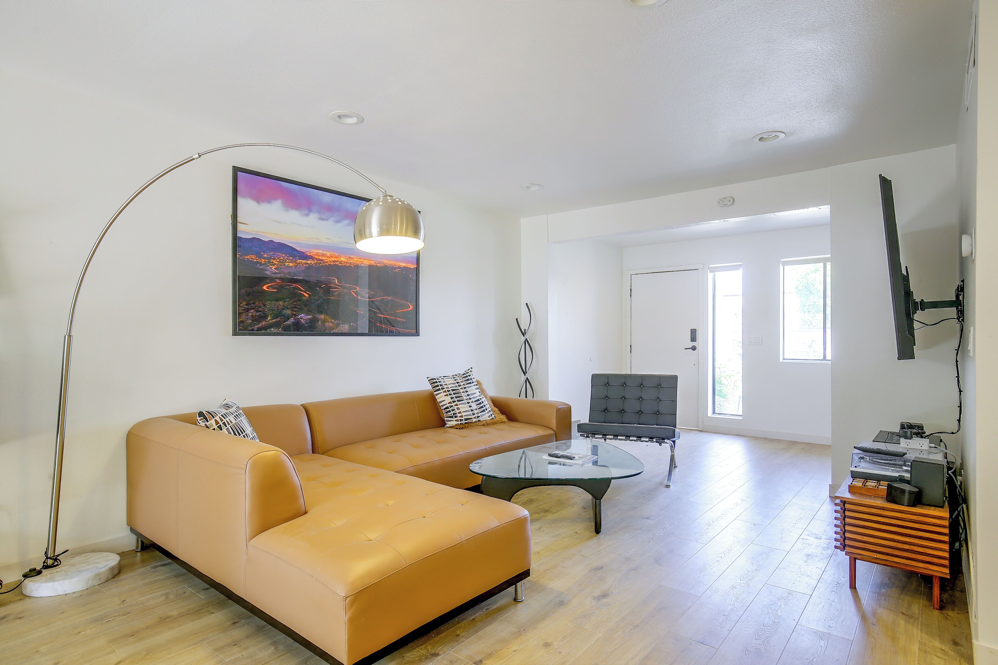 A spacious living room with a sofa, coffee table, and a painting of a landscape.