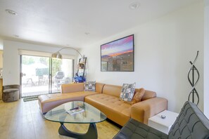 A modern living room with a glass coffee table, a tan sofa, and a large window. - Walk to El Paseo Shops! Palm Desert Condo w/ Patio (Palm Desert)