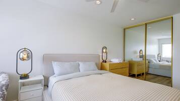 A bedroom with a bed, bedside tables, a wardrobe, and a ceiling fan.