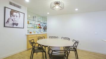 A dining area with a round table and four chairs, a kitchen area with a mirrored backsplash, and a ceiling light fixture.
