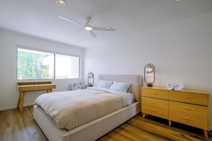 Ein Schlafzimmer mit einem Bett, einem Schminktisch, einem Schreibtisch und einem Deckenventilator.