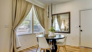 A dining area with a round table, two chairs, a potted plant, and a large mirror on the wall. - Historic Southside Fort Worth Home w/ Fenced Yard! (Fort Worth)