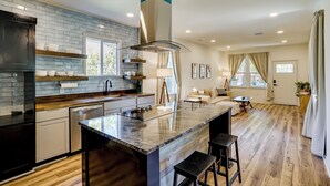 A modern kitchen with a central island, built-in appliances, and a large window. - Historic Southside Fort Worth Home w/ Fenced Yard! (Fort Worth)