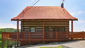 Une cabane en bois avec un balcon, une fenêtre et une porte.