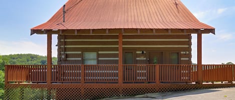 Une cabane en bois avec un balcon, une fenêtre et une porte.