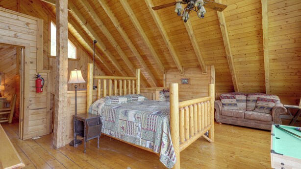L’intérieur d’un chalet en bois comprend un lit en mezzanine, un canapé et une table de billard.