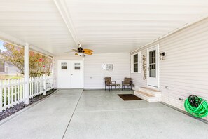 A covered porch with a ceiling fan, two chairs, a small table, and a green garden hose. - Yard & Screened Porch! Villages Escape (Lady Lake)