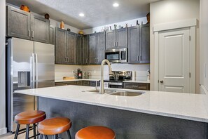 A modern kitchen with a central island, stainless steel appliances, and dark wood cabinets. - Explore Glen Canyon/lake Powell! Red River Retreat (Page)