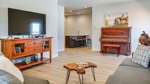 A living room with a television, wooden entertainment unit, and a piano. - Explore Glen Canyon/lake Powell! Red River Retreat (Page)