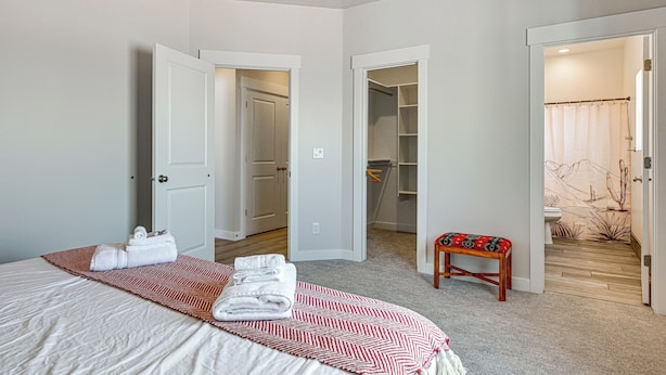 A bedroom with a bed, a walk-in closet, and a bathroom with a shower curtain. - Explore Glen Canyon/lake Powell! Red River Retreat (Page)