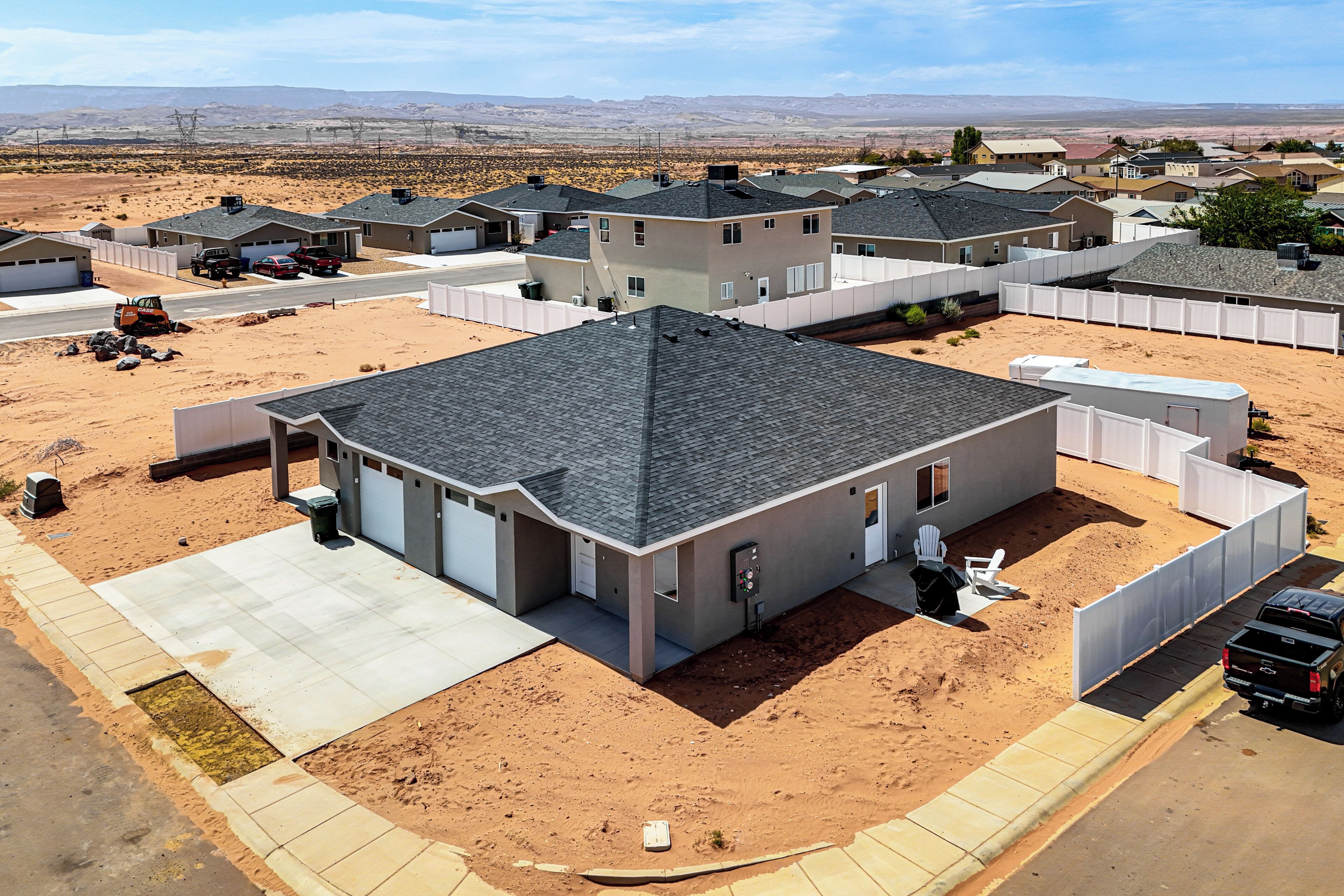 A residential area with houses, a paved driveway, and a clear sky.