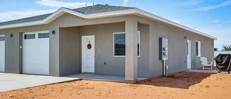 Uma casa térrea com garagem, porta da frente e varanda coberta.