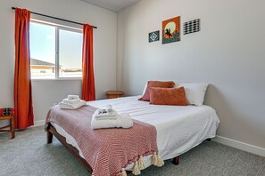 Una habitación de hotel con cama, mesita de noche, ventana con cortinas y decoración en la pared.