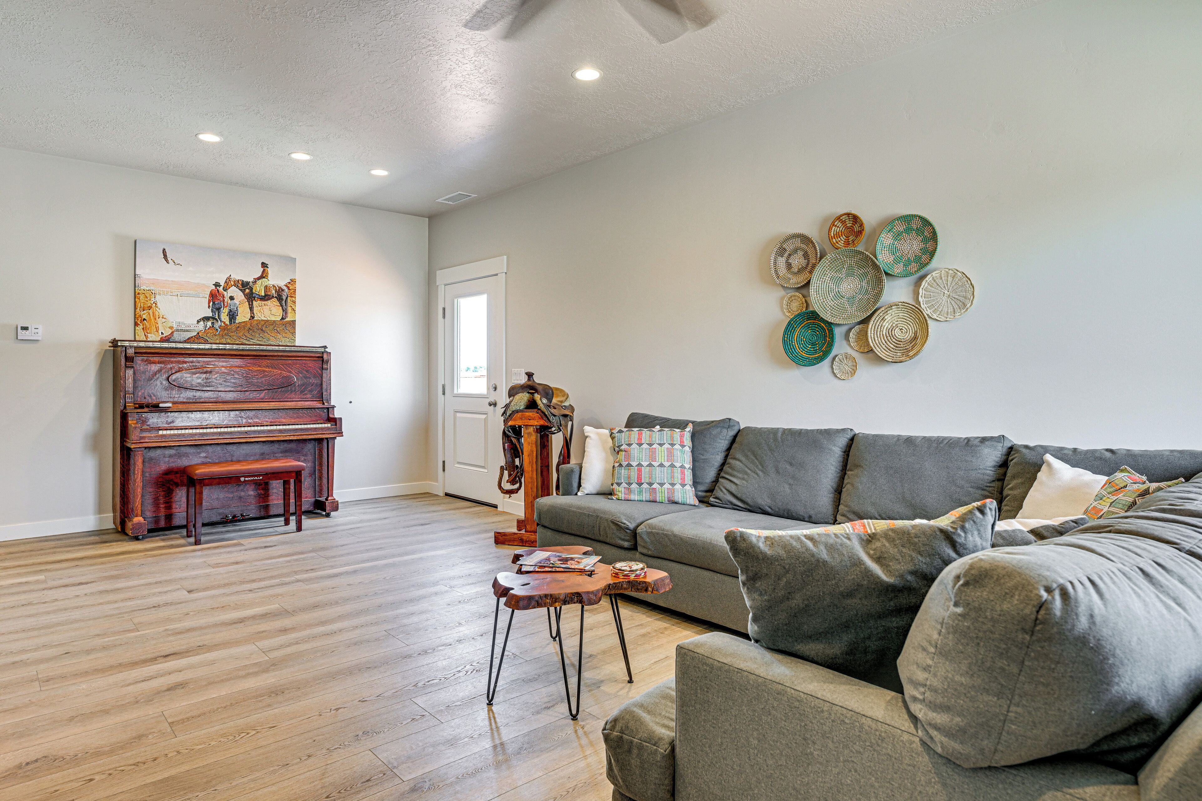 A living room with a grand piano, a sofa, a coffee table, and a wall with decorative plates.