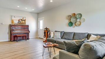 A living room with a grand piano, a sofa, a coffee table, and a wall with decorative plates.