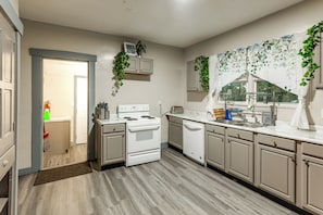 A kitchen with a stove, oven, dishwasher, and a window with a view.
