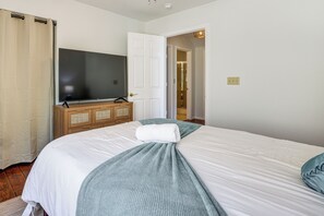 A bedroom with a bed, a television, a wooden dresser, and a door leading to another room. - Poolside Chills, Casino Thrills! Las Vegas Getaway (Las Vegas)