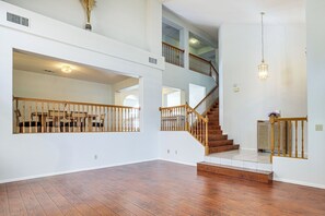 A spacious interior with a wooden staircase, white walls, and a high ceiling.