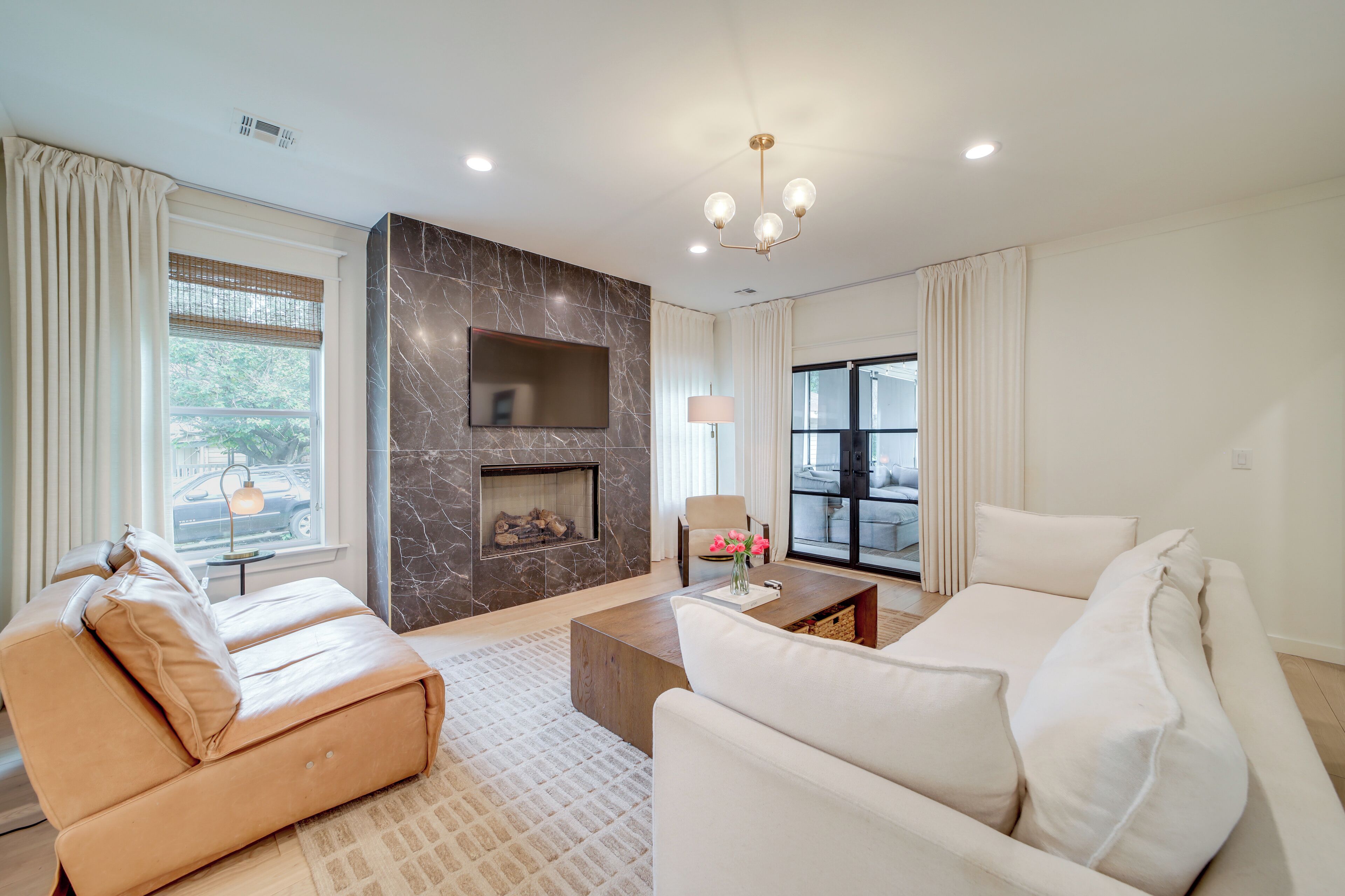 A modern living room with a fireplace, leather sofas, and a large window.