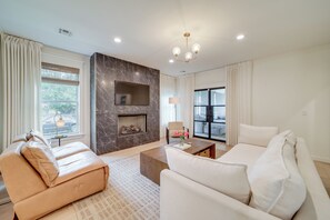 Una sala de estar moderna con chimenea, sofás de cuero y un ventanal grande.