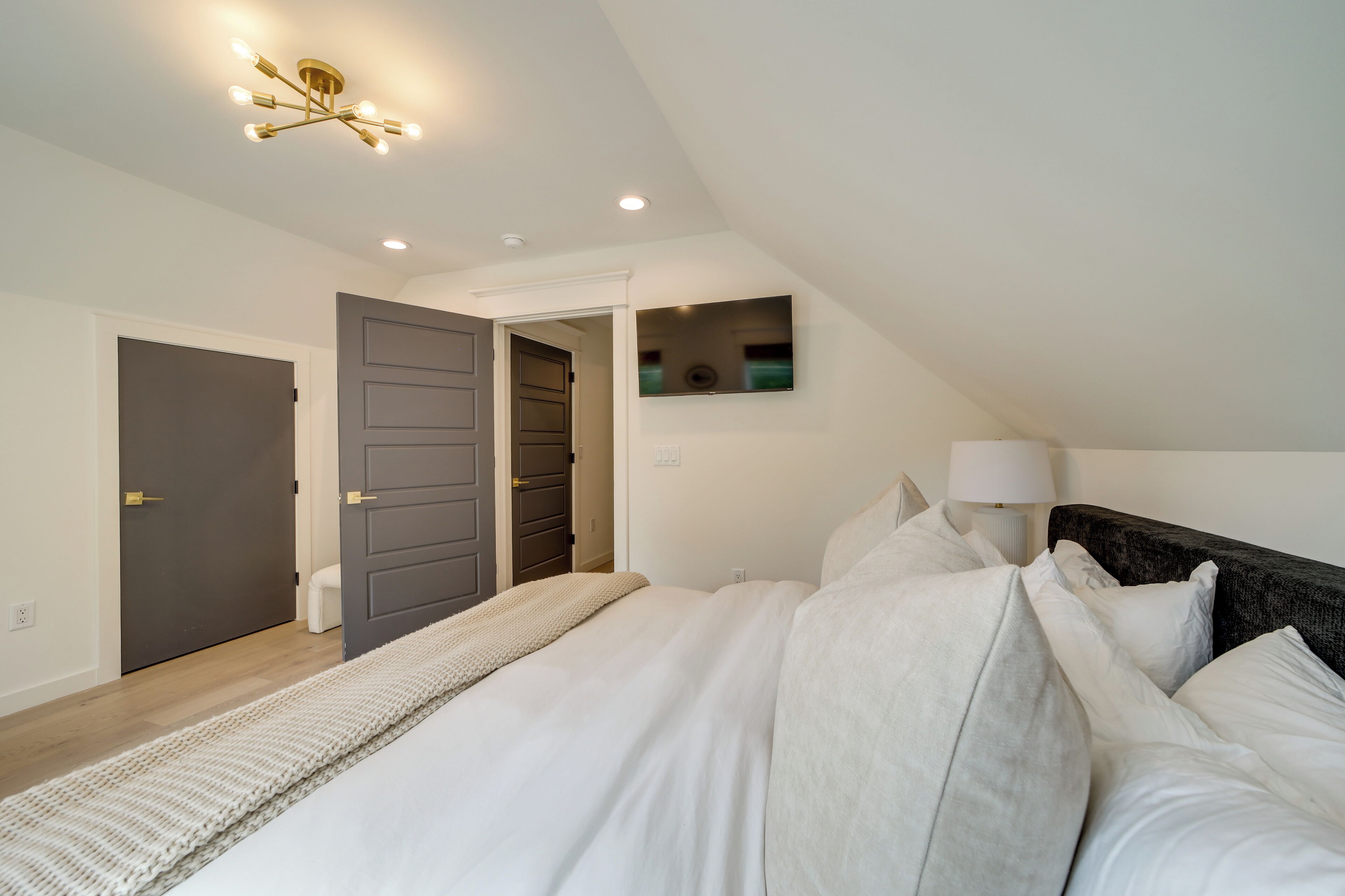 Een slaapkamer met een groot bed, een bedlampje en een plafondarmatuur.