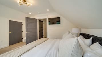 Een slaapkamer met een groot bed, een bedlampje en een plafondarmatuur.