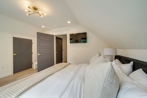 A bedroom with a large bed, a bedside lamp, and a ceiling light fixture.