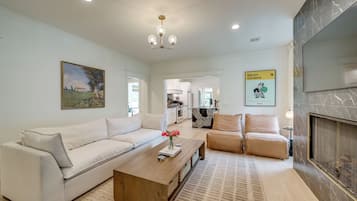 A modern living room with a white sofa, a wooden coffee table, and a fireplace.