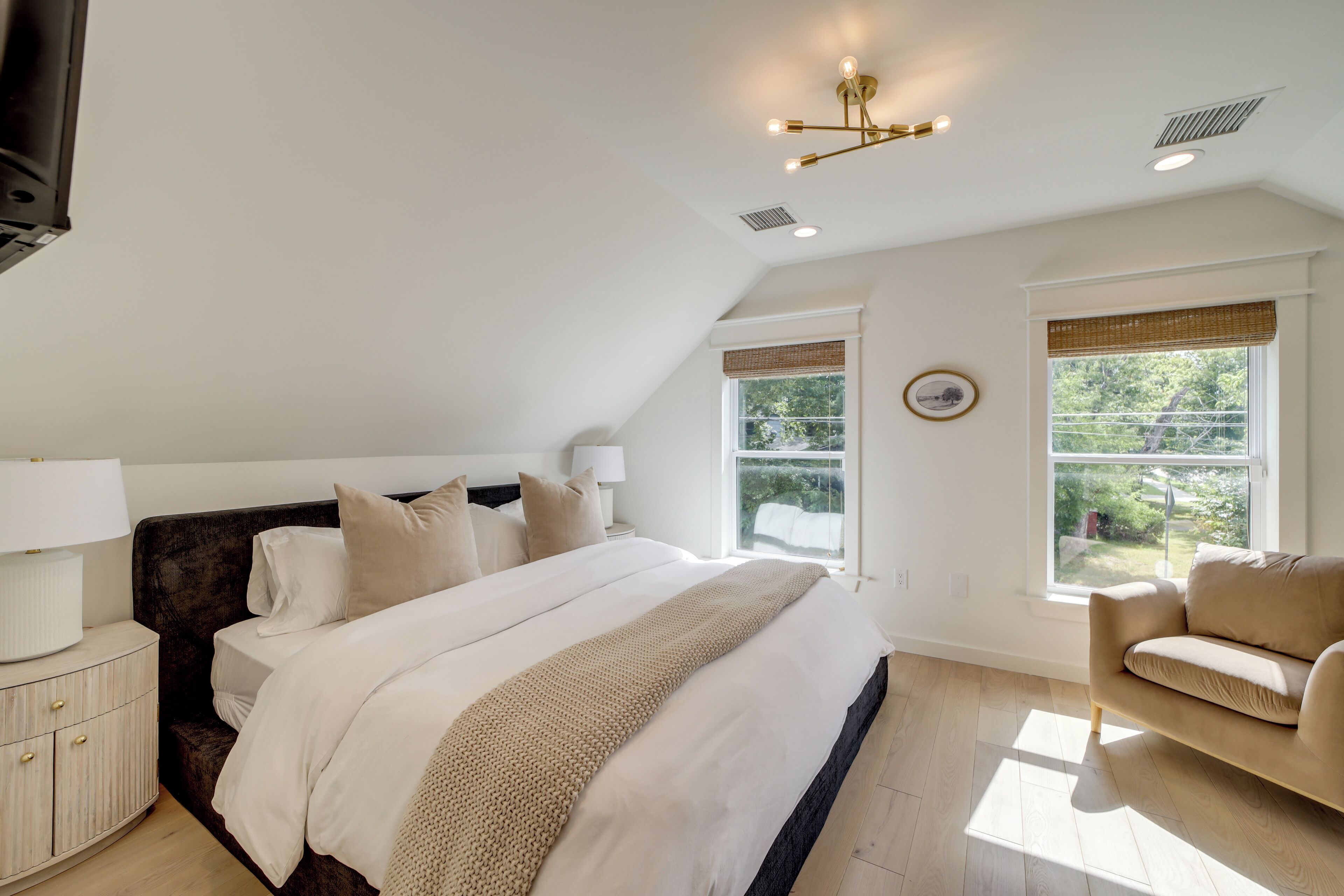 Een slaapkamer met een groot bed, een nachtkastje, een lamp, een raam met uitzicht en een plafondlamp.