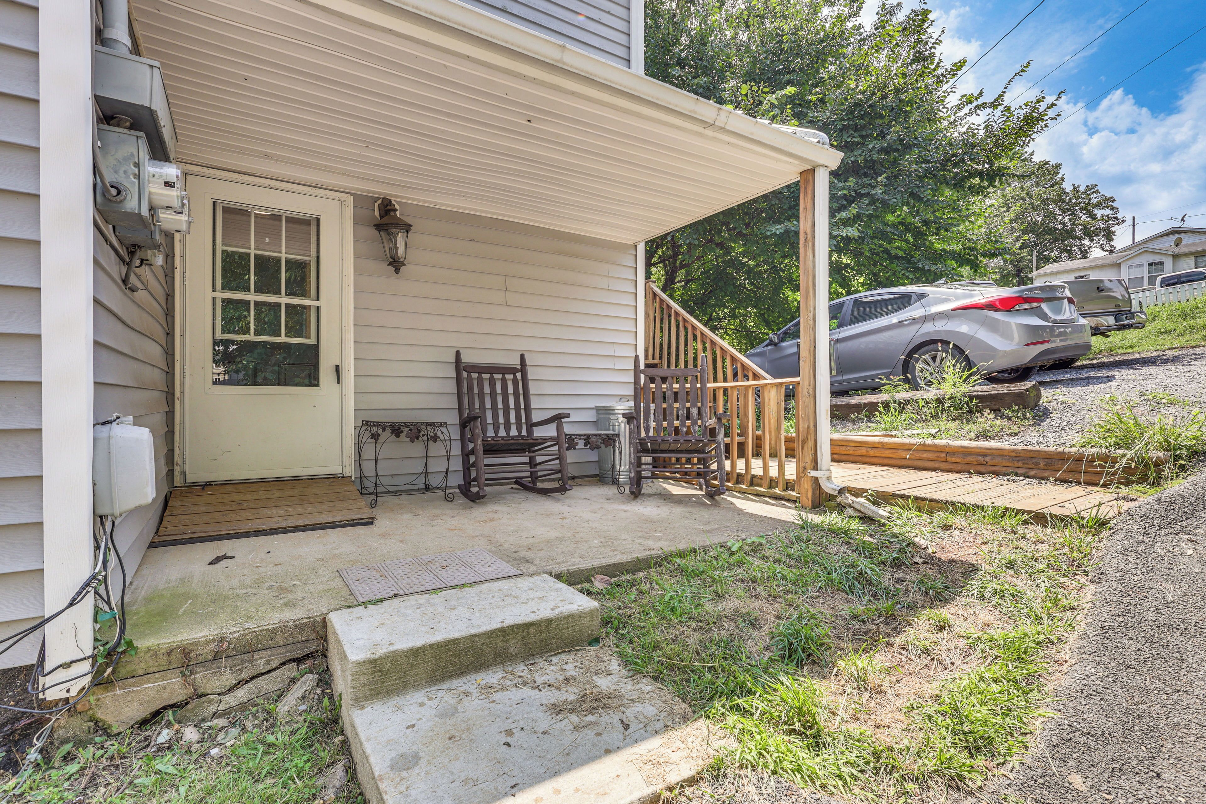 A covered porch with a wooden bench, a small table, and a step leading to the house.