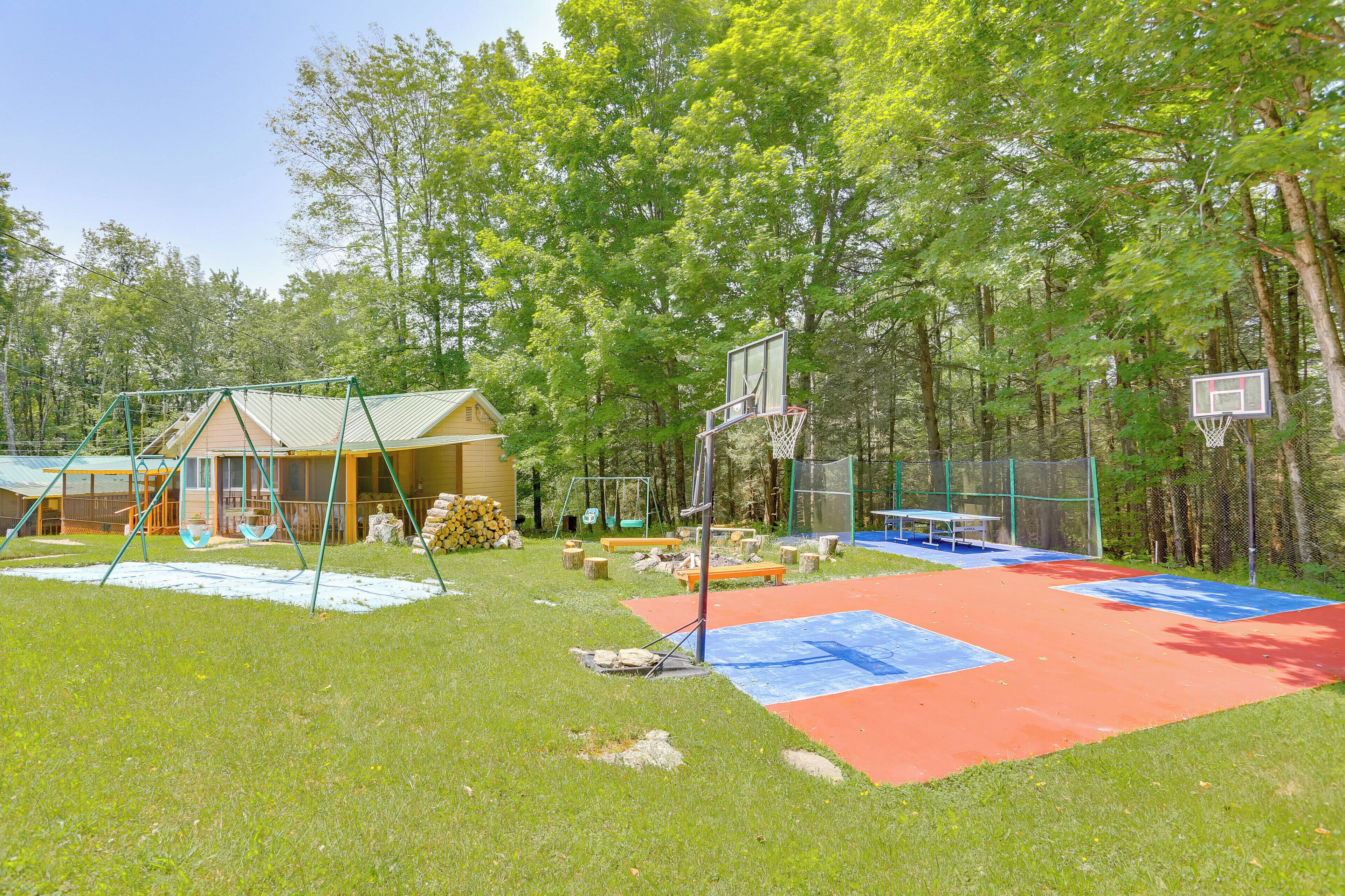 Un terrain de basket avec une balançoire et un petit bâtiment situé dans une zone boisée.