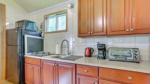 Eine Küche mit Holzausstattung, einem Edelstahlkühlschrank, einem Gasherd, einem Spülbecken, einem Fenster und einem Toaster.