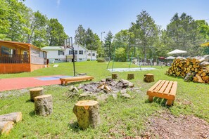 Ein Garten mit einer Holzbank, einem Feuerkorb und einem Basketballkorb.