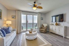 A living room with a sofa, armchair, coffee table, and a television on a cabinet. - Gulf Views & Beach Access! 2 PCB Condos w/ Pool! (Panama City Beach)