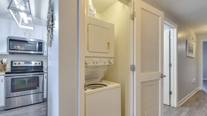 Een kleine keuken met een magnetron, oven en een wasmachine.